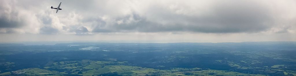 A picture taken from an aircraft in the air over countryside, and of another aircraft in the air