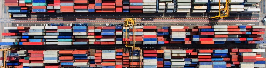 A bird's eye view of many rows of various coloured shipping containers from above.