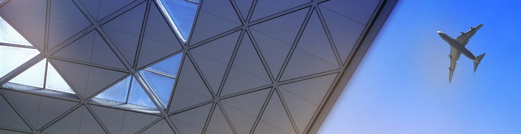 A plane flying over the roof of an airport.