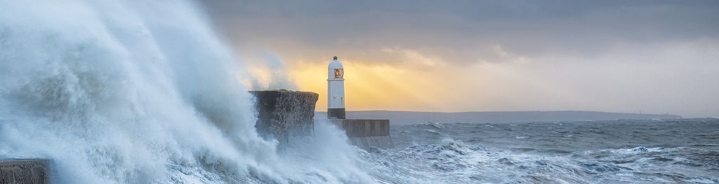 Waves crashing against a lighthouse during a sea storm.