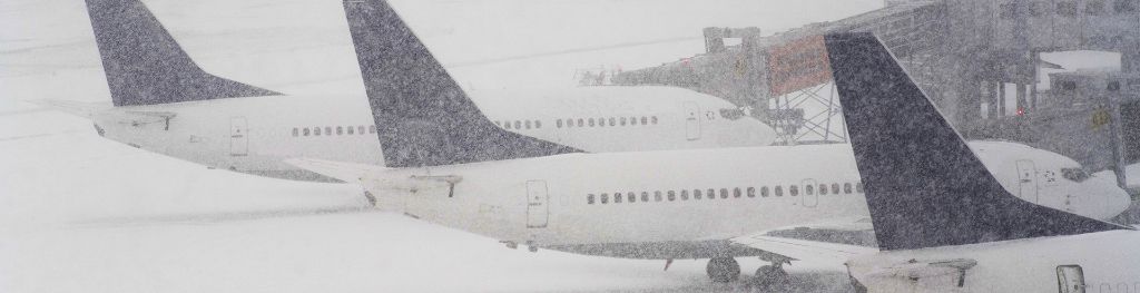 Three passenger aircrafts grounded at an airport due to snow.