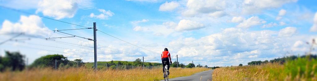 Back on man cycling on an empty road in summer