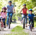 Family of four with a girl and a boy cycling on a path through the forest