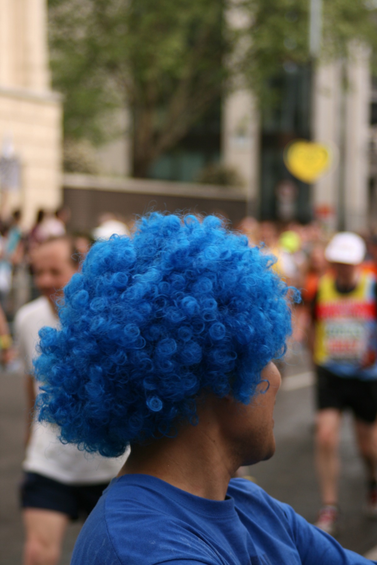 Man wearing a blue wig with curly hair.